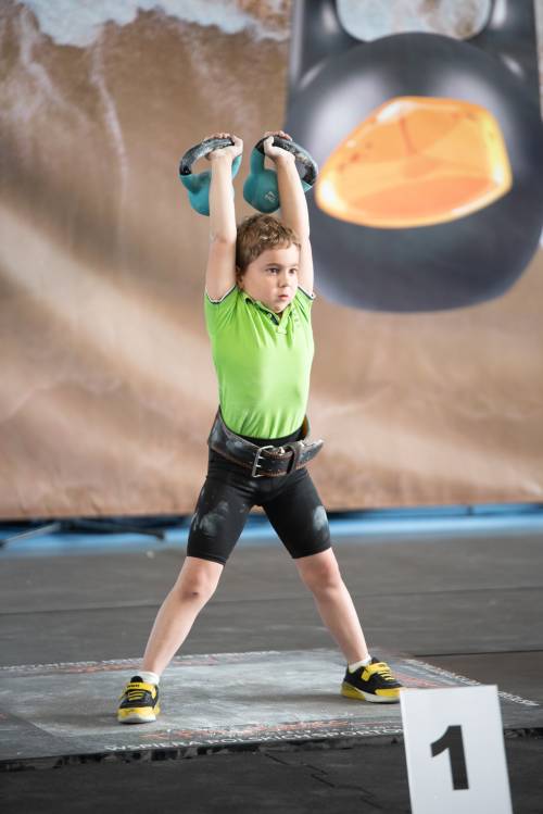 6-letni zawodnik podczas konkurencji - z rękami podniesionymi do góry.